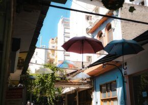 an alleyway with umbrellas and buildings in the background